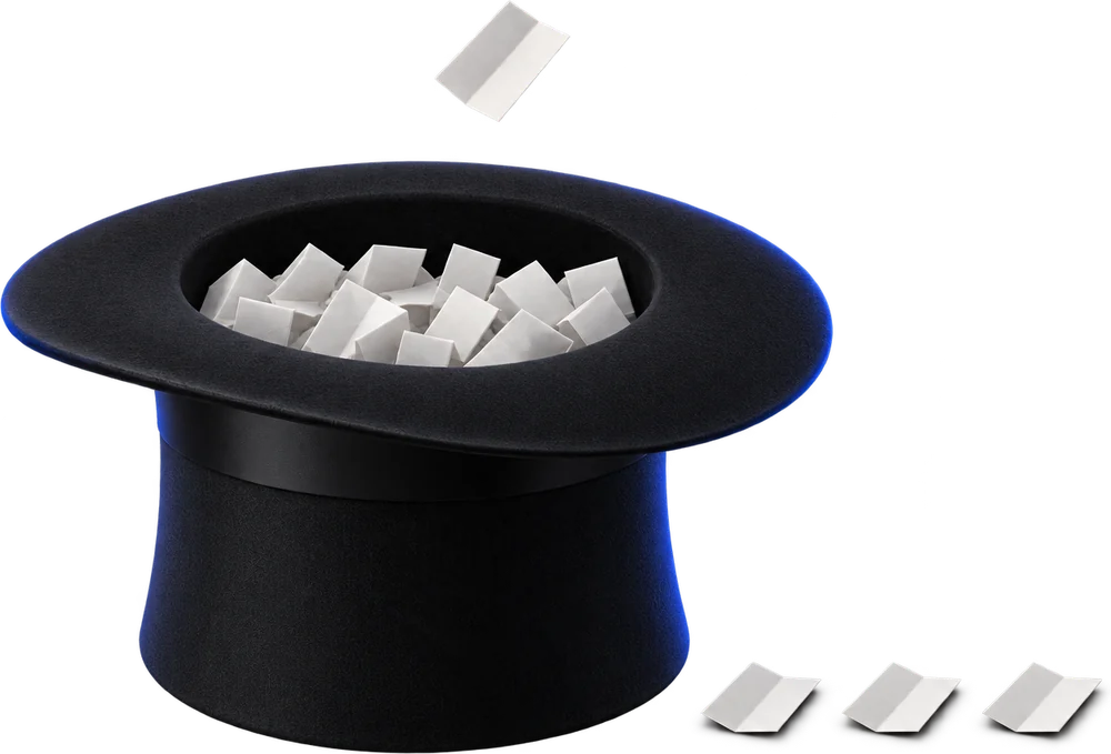 A hat filled with identical folded tickets. One ticket is in the air just above the opening, and three already-drawn tickets lie flat beside the hat.